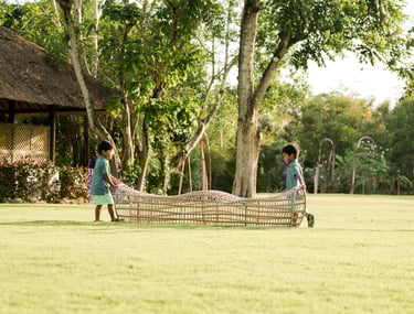 mother kneeling and embracing her children on the lawn at rimba by ayana bali during natural bali family photography
