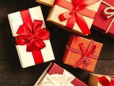 variedad de cajas de regalos con moño rojo sobre una mesa