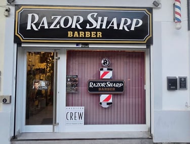 Exterior of Razor Sharp Barber shop storefront with traditional pole and American Crew sign.