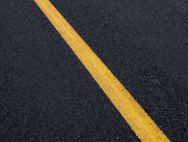High-resolution photography of a modern asphalt texture with painted yellow lines, symbolizing quality road construction and communication routes.
