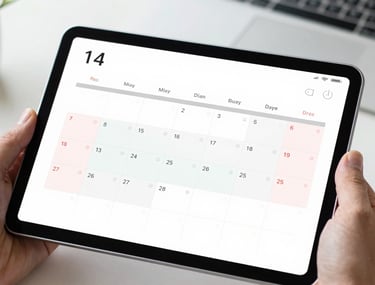 A focused close-up of a digital calendar on a tablet screen showing organized business deadlines and reminders. The tablet is held by a professional in a modern North American / US workspace. Bright and clean lighting.