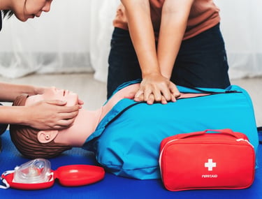 Two people practising CPR on a dummy in First Aid training