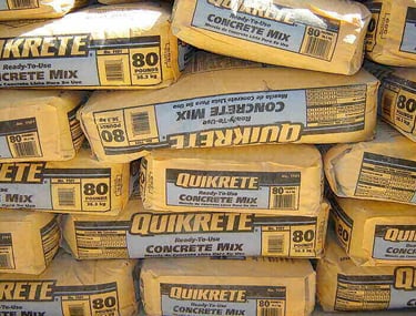 Stacks of 80lb pre-mixed concrete bags ready for a residential post installation project.