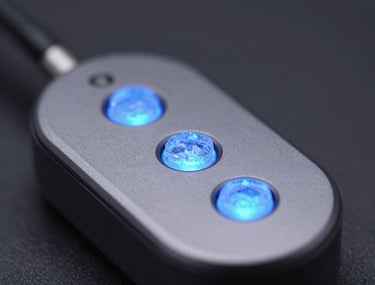 A macro shot of a sleek technological device with glowing ice blue indicators. The background is a blurred deep charcoal, focusing on the high-quality finish and precision assembly.
