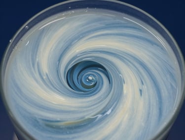 Close-up high-speed photography of a scientific fluid experiment, showing intricate turbulence patterns with precise focus. Light blue and off-white tones against a dark navy background.