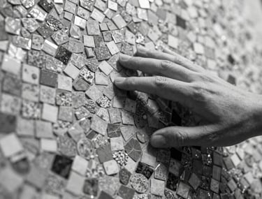 A designer hand touching a textured mosaic surface, close-up, black and white photography style, showing the craftsmanship and detail of the material.