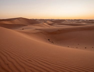 A wide cinematic shot of a North American desert at sunrise, with warm terracotta and soft sand colors dominating the landscape.