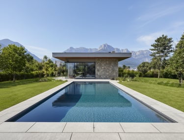 Rectangular photograph of a modern rectangular luxury pool with clear blue water and mountain backdrop.