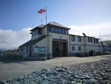 Borth RNLI Lifboat station viewed from the slipway and beach with blue skies