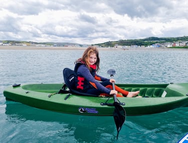 a young in a wetsuit sitting in a kayak