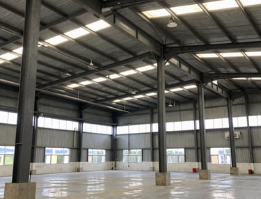 Steel warehouse structure in mid-construction showing heavy steel beams and concrete foundation.