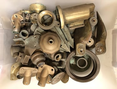 A bin full of various brass parts inside an assemblage artist's studio.