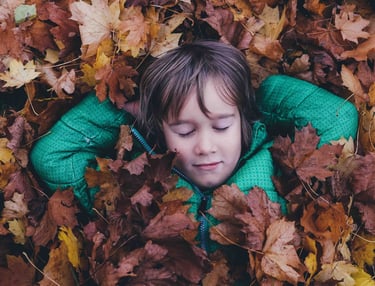 child resting in leaves