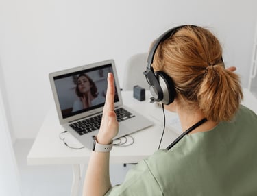 a woman in a green shirt is sitting at a desk with a laptop and head