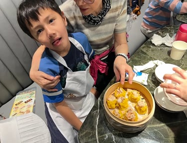 家長陪同孩子一同製作燒賣，雙手合作包裹餡料，展現親子參與與互相支持的溫馨互動。