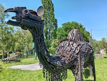 A life-sized camel sculpture made from recycled scrap metal standing in a green park.
