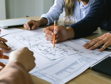 Hands of stakeholders refining a detailed diagram, illustrating adaptive and precise approaches