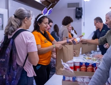 Volunteers distributing canned goods and food donations at a community food bank or charity event.