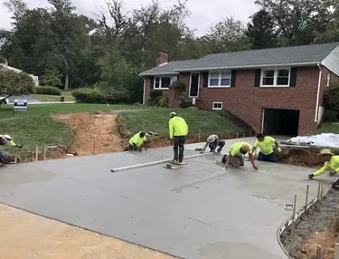 a group of men in yellow jackets and yellow jackets working on a concrete slab