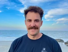 Profile picture of mustachioed man against a seashore background