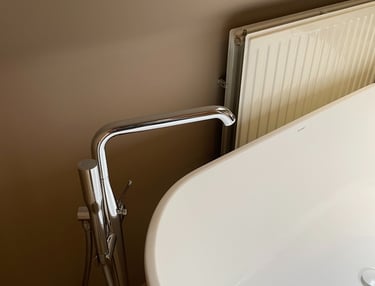 Vrijstaand bad met vloermontage badkraan en verticale radiator onder dakraam in moderne badkamer