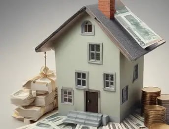 Symbolbild für Immobilienwert: Hausmodell mit Geldscheinen und Münzstapeln.