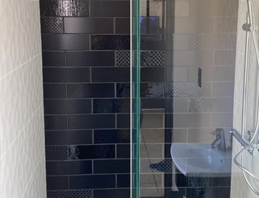 Douche avec faïence métro noire à plusieurs motifs et retours en blanc texturé