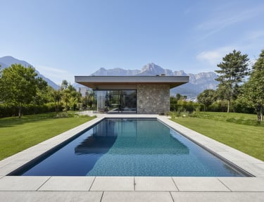 Rectangular photograph of a modern rectangular luxury pool with clear blue water and mountain backdrop.