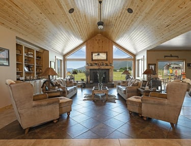 a living room with a fireplace and large windows with Montana mountains outside