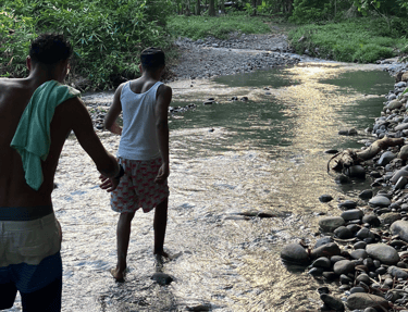 Two men cross the river near camping babsita in costa rica