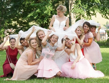 photography og a bride with best women plaing under her wedding dress, they smile and laugh.