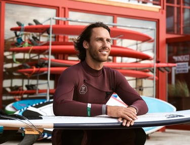 a man in a wetsuit is holding a surfboard