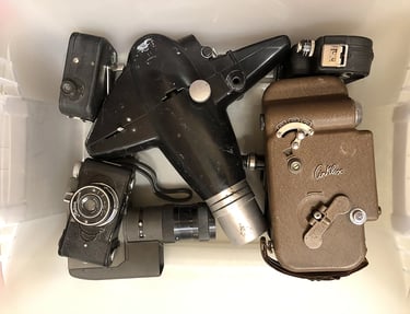 A bin full of old cameras inside an assemblage artist's workshop.