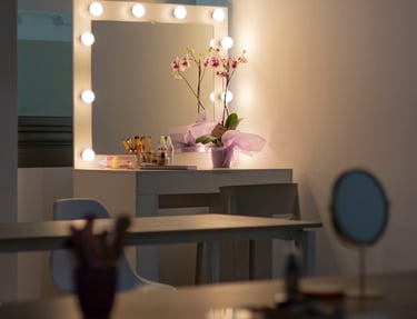 Tocador de maquillaje profesional con espejo Hollywood iluminado, planta de orquídea y herramientas 