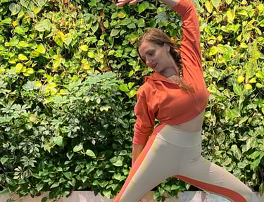 a woman in a red shirt and white pants doing yoga