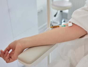 Patient receiving IV drip therapy treatment in a bright, modern medical clinic setting.