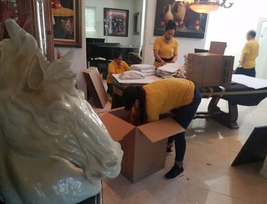carefully packing household items into moving boxes