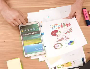 Hands holding a smartphone with a colorful interface and a paper with pie charts, symbolizing GMAT