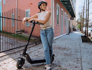 a woman in a helmet and helmet on a scooter