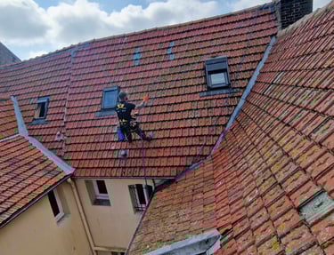 cordiste qui intervient sur une toiture en tuiles