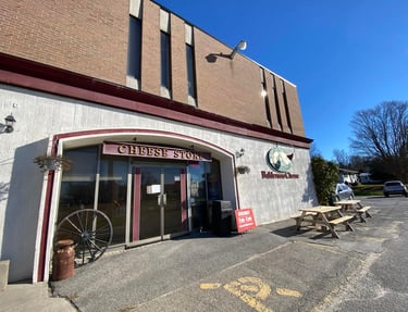Exterior view of the Balderson Cheese Store storefront with outdoor picnic tables and rustic decor.