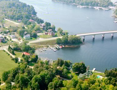 Aerial view of a scenic river with a concrete bridge, waterfront homes, and private boat docks.