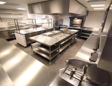 Professional stainless steel kitchen with industrial prep benches and cooking equipment for our Frequently Asked Questions.