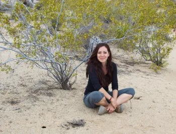 woman sitting among plants on desert sands