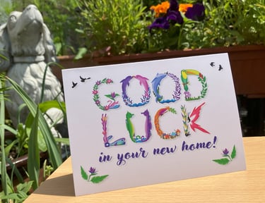 A greeting card with the words Good Luck in you're new home printed in tropical exotic word art