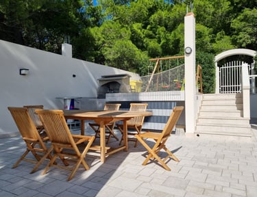 The photo shows a dining table with a grill in the central courtyard and the main entrance.