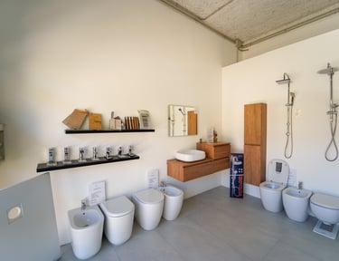 Modern bathroom showroom display featuring ceramic toilets, bidets, chrome faucets, and rain shower heads.