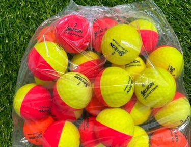 A clear bag of Srixon Z-Star Divide yellow and red dual-color golf balls on artificial green turf.
