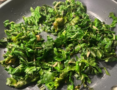 Fresh chopped green kale sautéing in a nonstick frying pan with garlic.