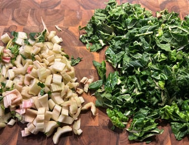 Chopped fresh Swiss chard leaves and diced stems on a wooden cutting board for meal prep.
